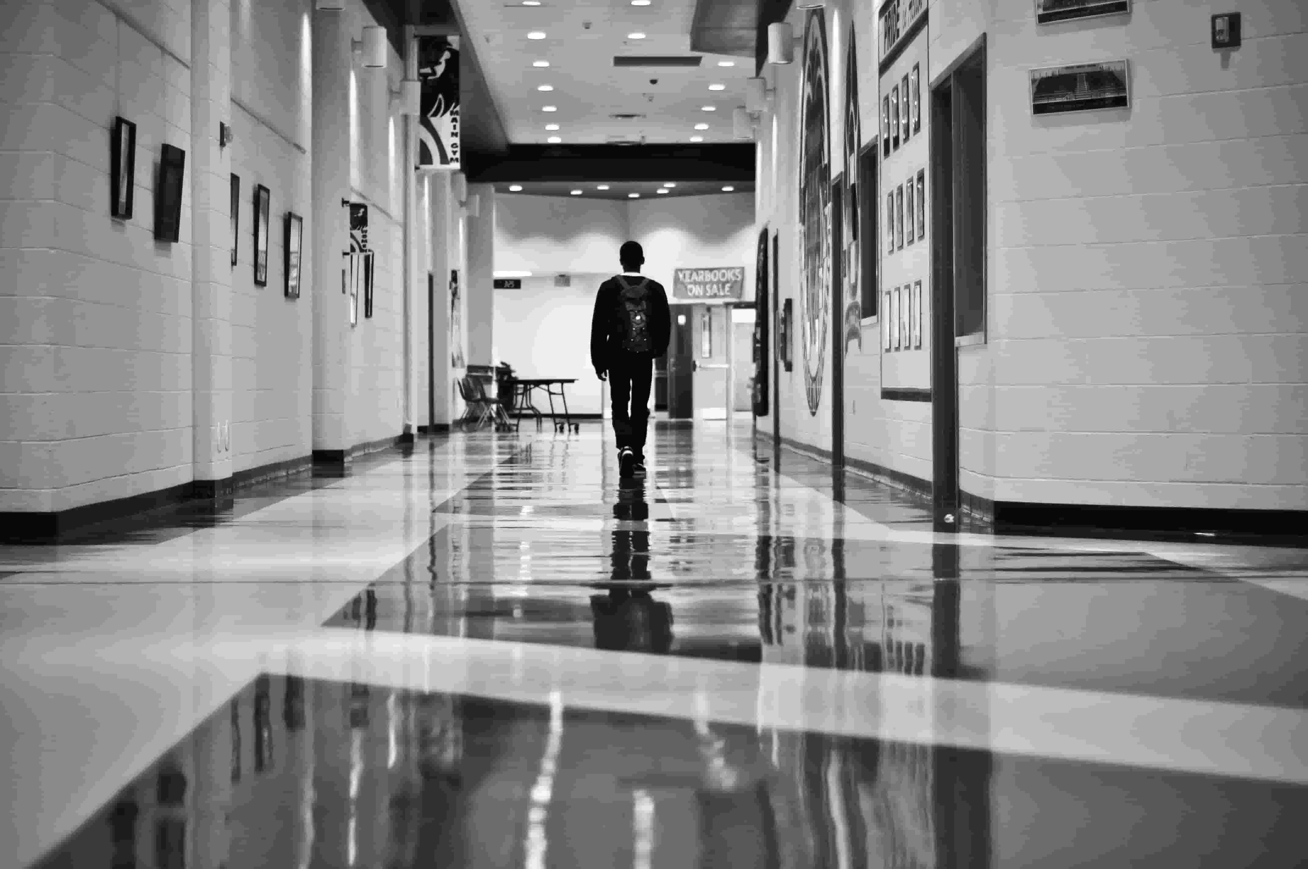 Lone figure walking in high school hallway